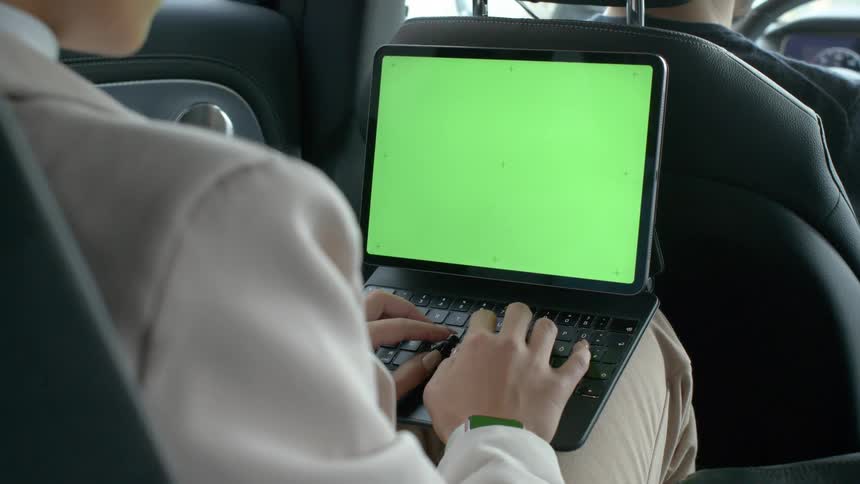 Female passenger working from her laptop in a ride share vehicle