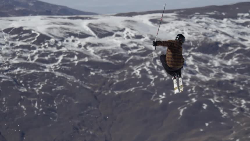 A skier does a trick on a ski slope