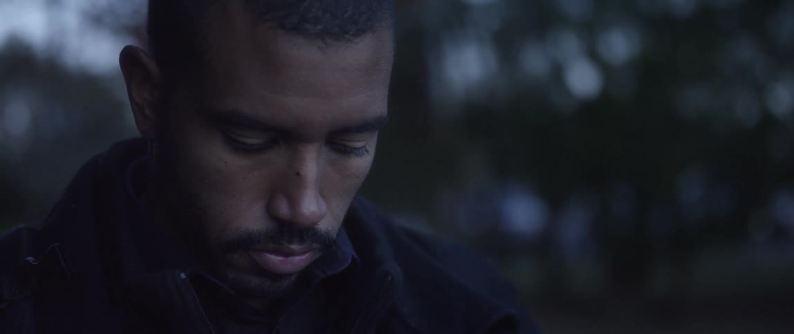 A black man deep in thought in an exterior setting