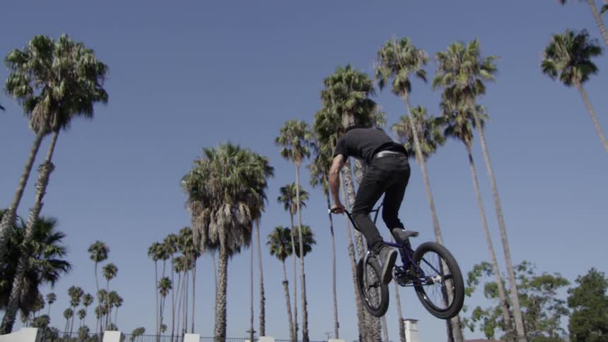 A guy does tricks on a bike at a skatepark