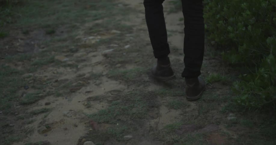 Legs walking on a grass and dirt covered area