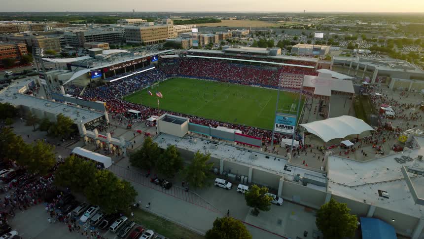 An aerial view of a packed soccer stadium during a match with a large crowd filling the stands