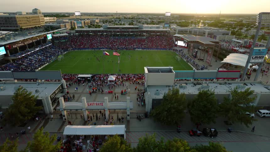 An aerial view of a packed soccer stadium during a match with a large crowd filling the stands
