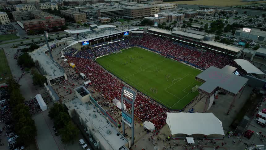 An aerial view of a soccer game is taking place at dusk in a stadium