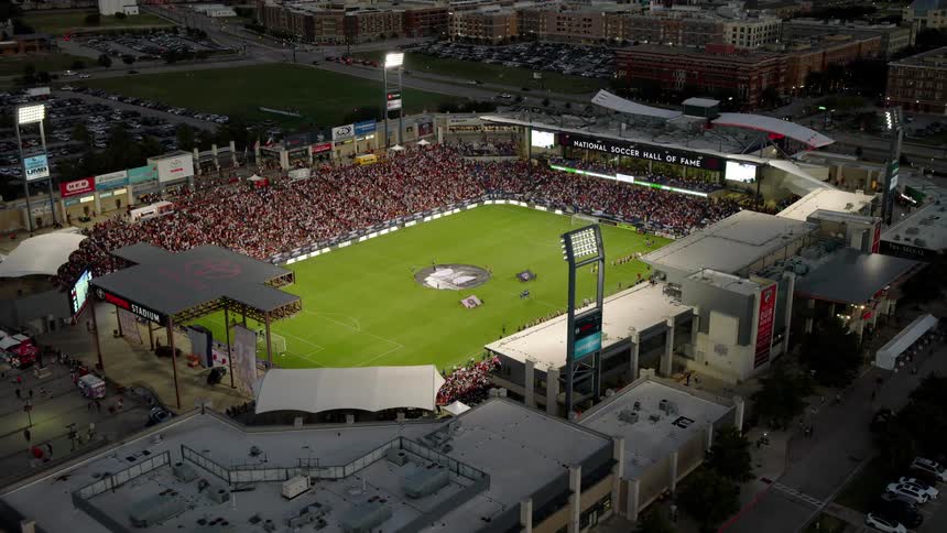 Soccer fans fill a stadium located in the city during the evening