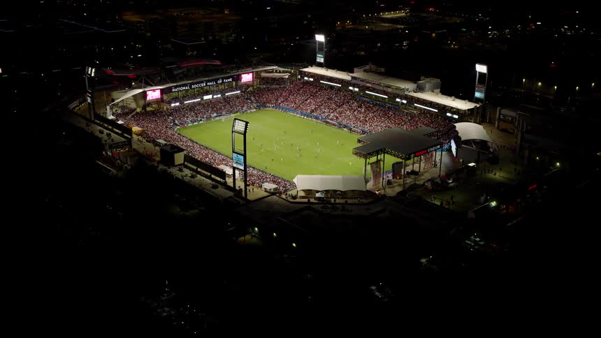 Soccer fans watch a soccer game in a stadium at night