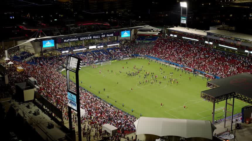 A large crowd is watching a soccer game at night