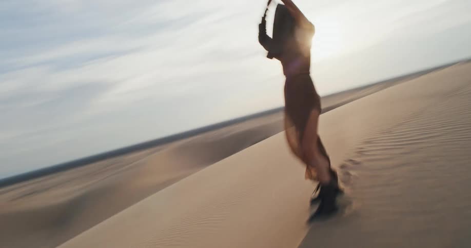 Lone woman poses on a dune in the desert on a cloudy day