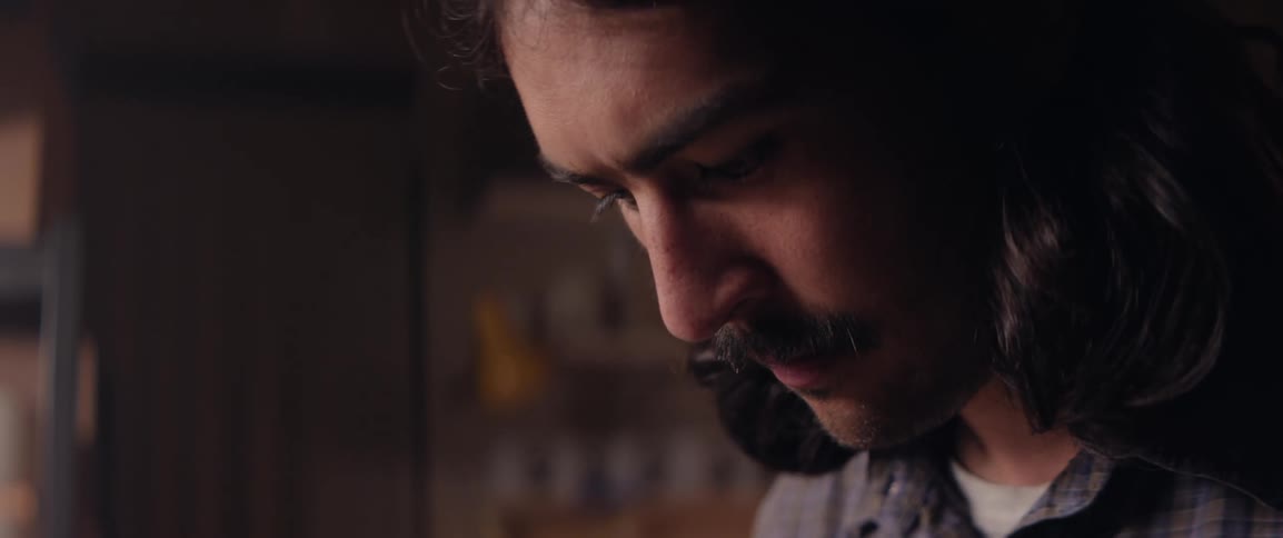 Close up of the face of a man with long hair and a mustache deeply focused in craft