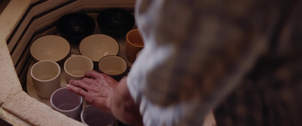 A clip of a person removing a freshly fired cup from the kiln