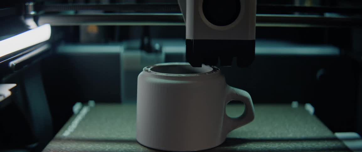 A 3d printer layers filament constructing an intricately detailed ceramic mug