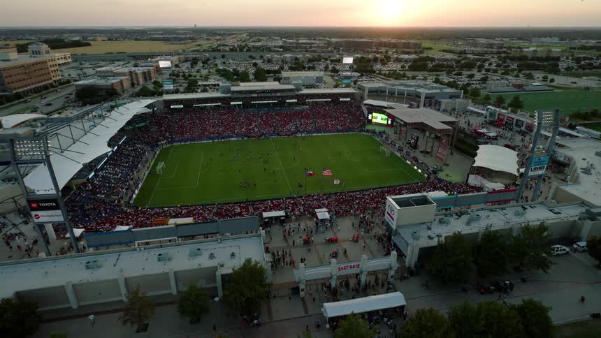 An aerial view of a packed soccer stadium during a match with a large crowd filling the stands