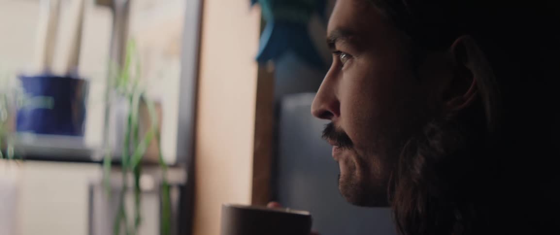 Side portrait of a man drinking steaming liquid from a mug
