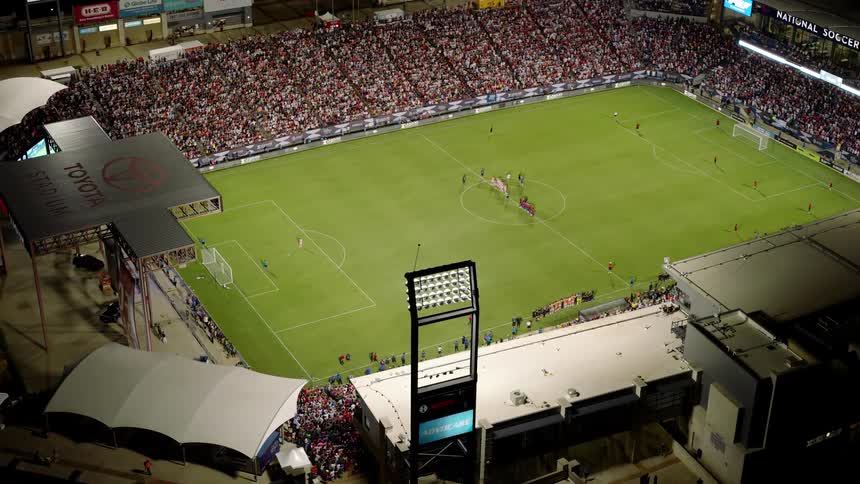 Soccer fans fill the stadium seats at a soccer game during the night