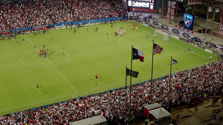 Professional players running on a field surrounded by stands full of spectators at a stadium