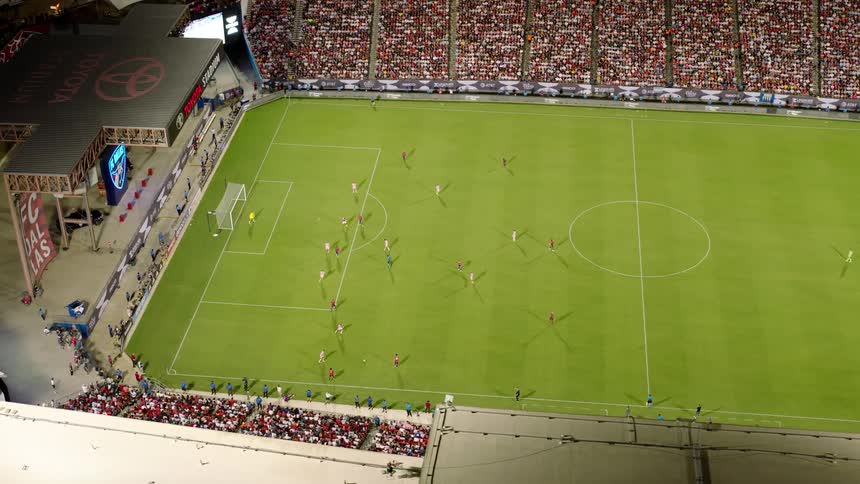 Soccer players are lined up on a field ready to play in an arena full of fans