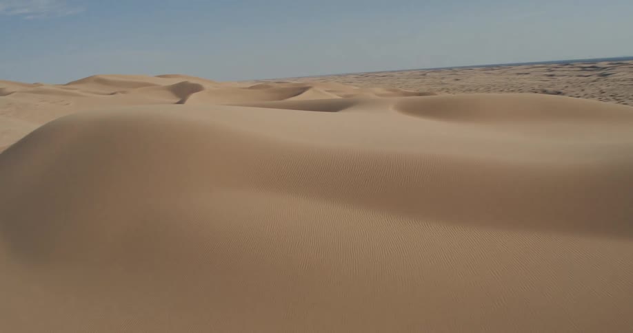 A vast expanse of sand dunes under a clear sky on a desert landscape