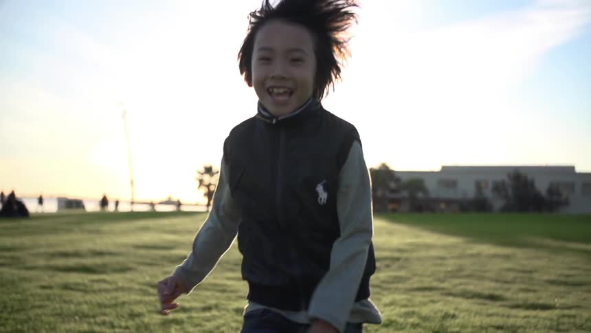 Child running down a field on a cloudy day