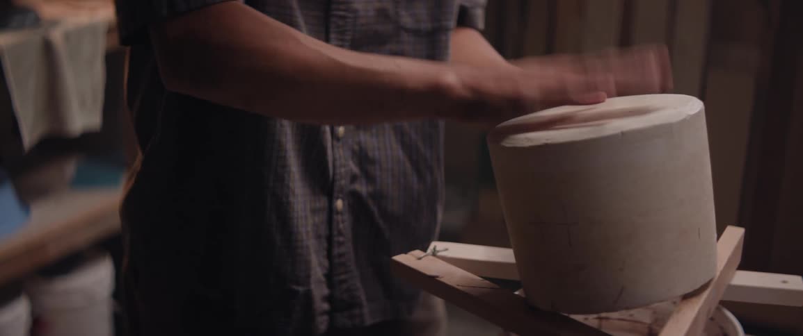 Male potter working in his workshop empties mixture into a bucket