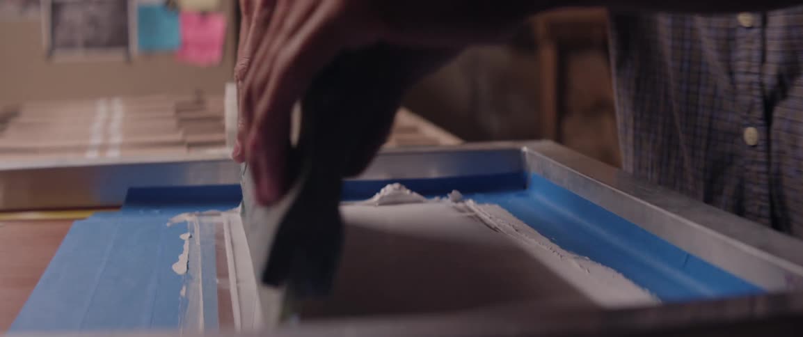 A person screen prints graphics onto a cardboard box