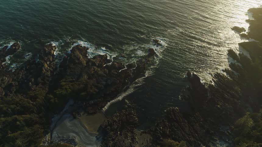 Water crashes on the rocks of the sea shore at sunset