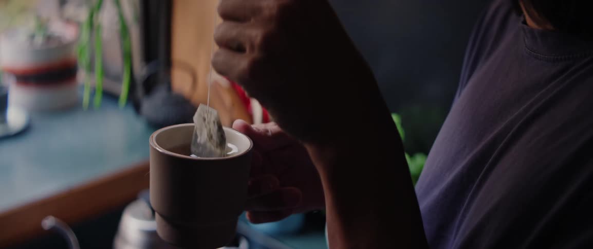 Person dips a tea bag into a mug of hot water