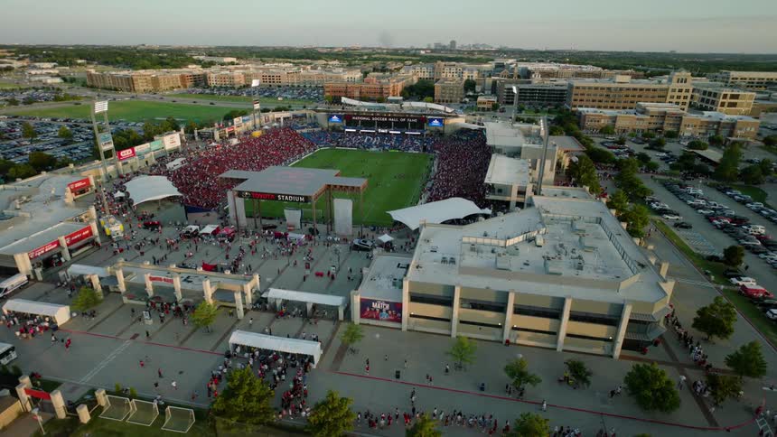 An aerial view of a stadium with a green lawn and a grandstand full of people