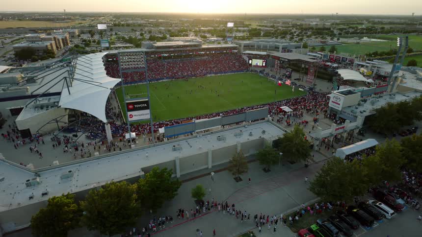 Aerial view of a soccer game is taking place at dusk in a stadium