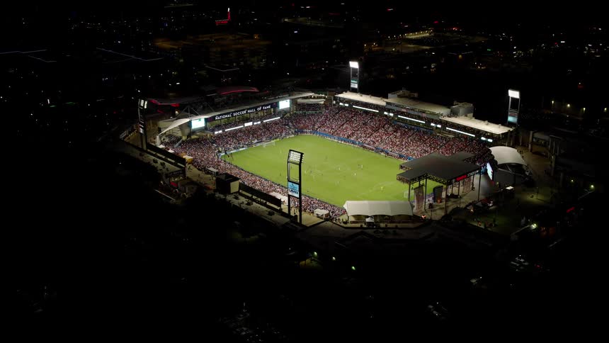 An aerial view of a packed soccer stadium during a match with a large crowd filling the stands