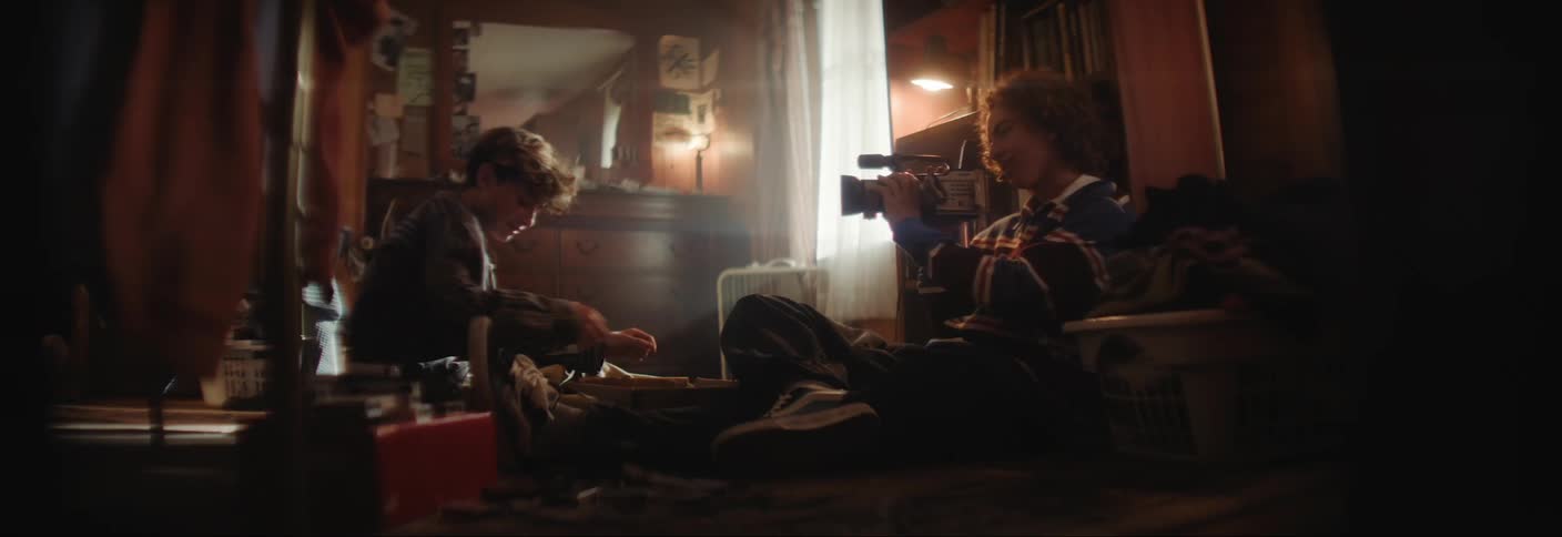 A teenager is looking at his camera in a dark room