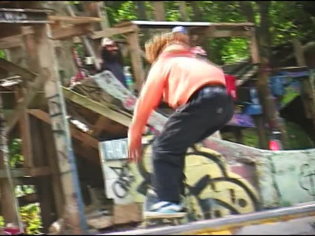 A teen is performing skateboarding tricks ramps in a graffiticovered wooden skate park structure