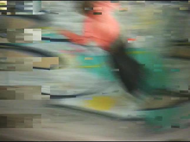 A young person in an orange jacket standing on a skateboard and doing tricks on ramps that are covered in graffiti