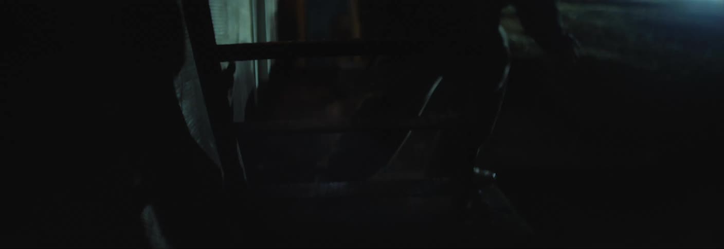 A man is fleeing down an outdoor staircase at night while another man chases him from behind