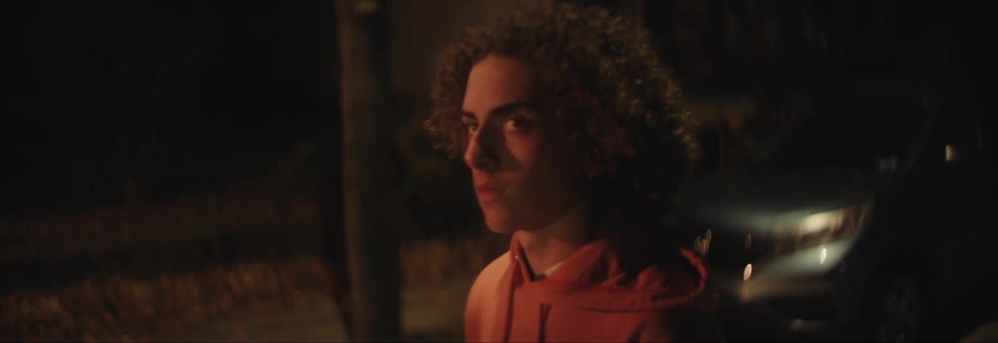 A teenager is walking past homes at night