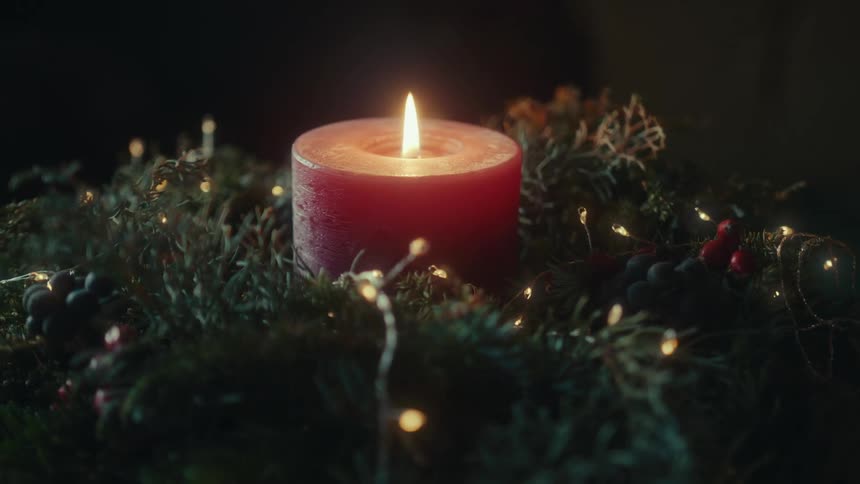 Red candle lit in a christmas decoration with lights