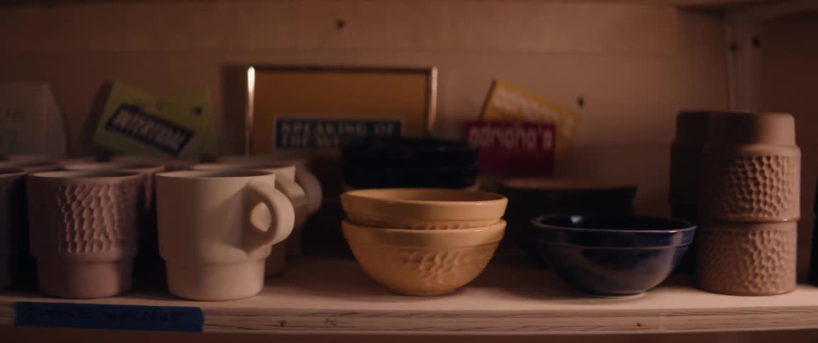 Person stacks clay bowls onto a shelf with other tableware