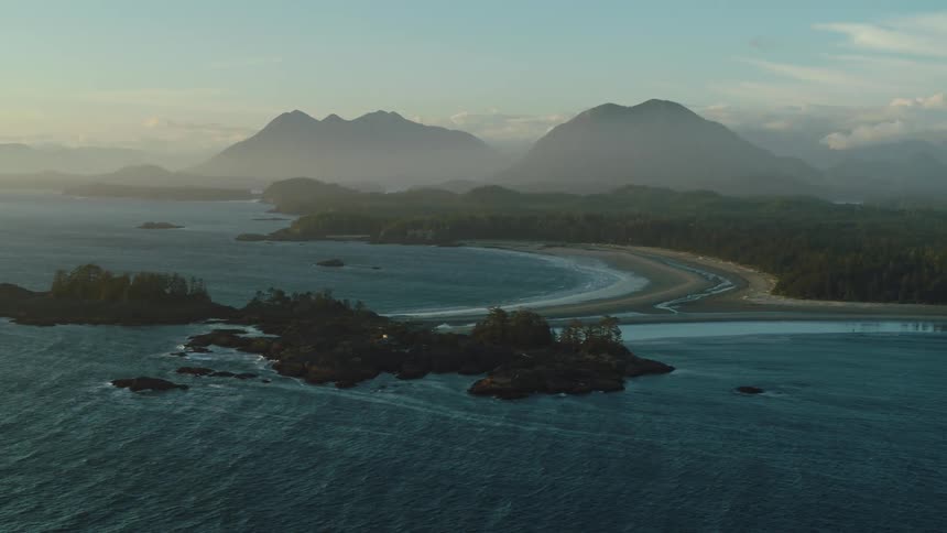 A serene coastal landscape with beaches framed by lush green islands and majestic mountains