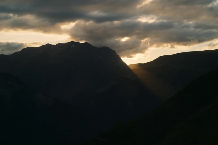 The sun rises behind some mountains