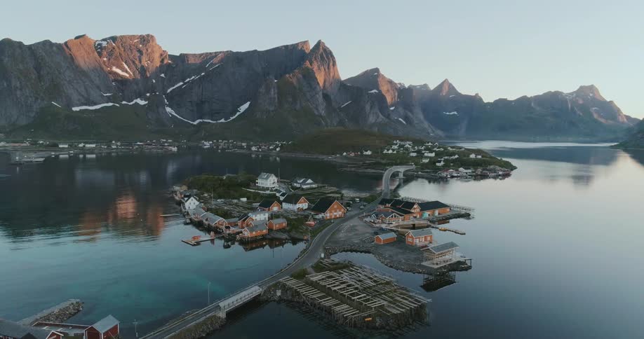 An aerial view of sakrisy a picturesque village in the lofoten archipelago norway with colorful houses reflected in the calm water and mountains towering in the background