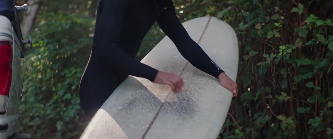 A clip of a man waxing a surfboard