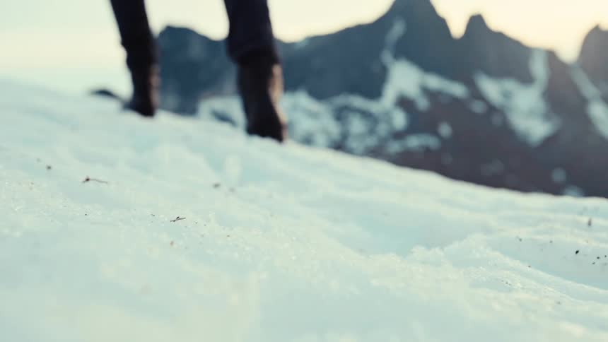 A person wearing black boots walks off in the snow