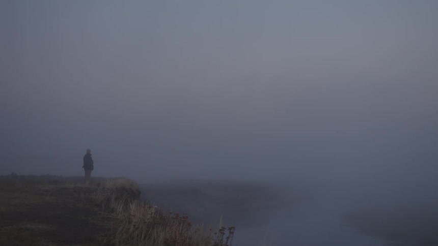 A person is standing in the distance covered by thick fog