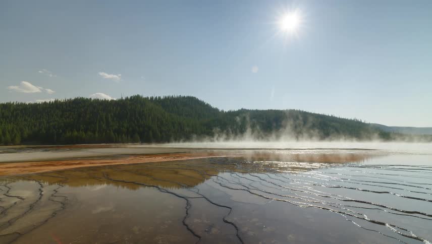 A vibrant geothermal hot spring its waters reflecting a brilliant blue sky as steam rises from its mineral rich surface creating a mesmerizing spectacle of nature
