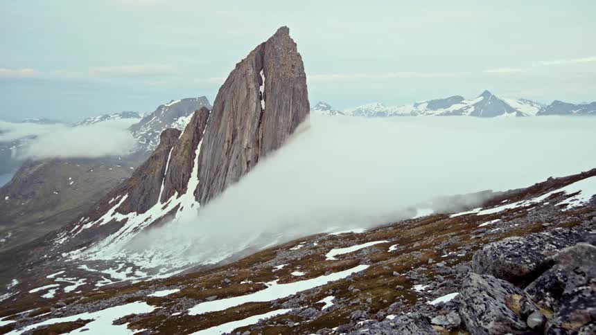 Clouds roll down a mountain