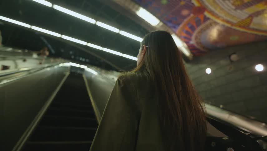 Woman with a bag going up the escalator
