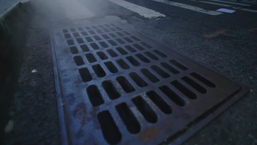 Stream rising from metal vent from an underground sewer in the city