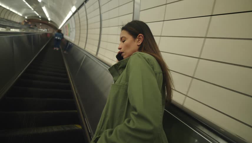 Woman on an escalator talking on her cell phone