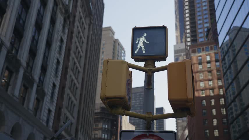 A pedestrian crosswalk signal changes from a red hand indicating dont walk to a white walking figure indicating walk in a city setting