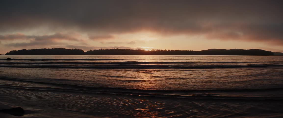 Waves wash up on a beach at sunset