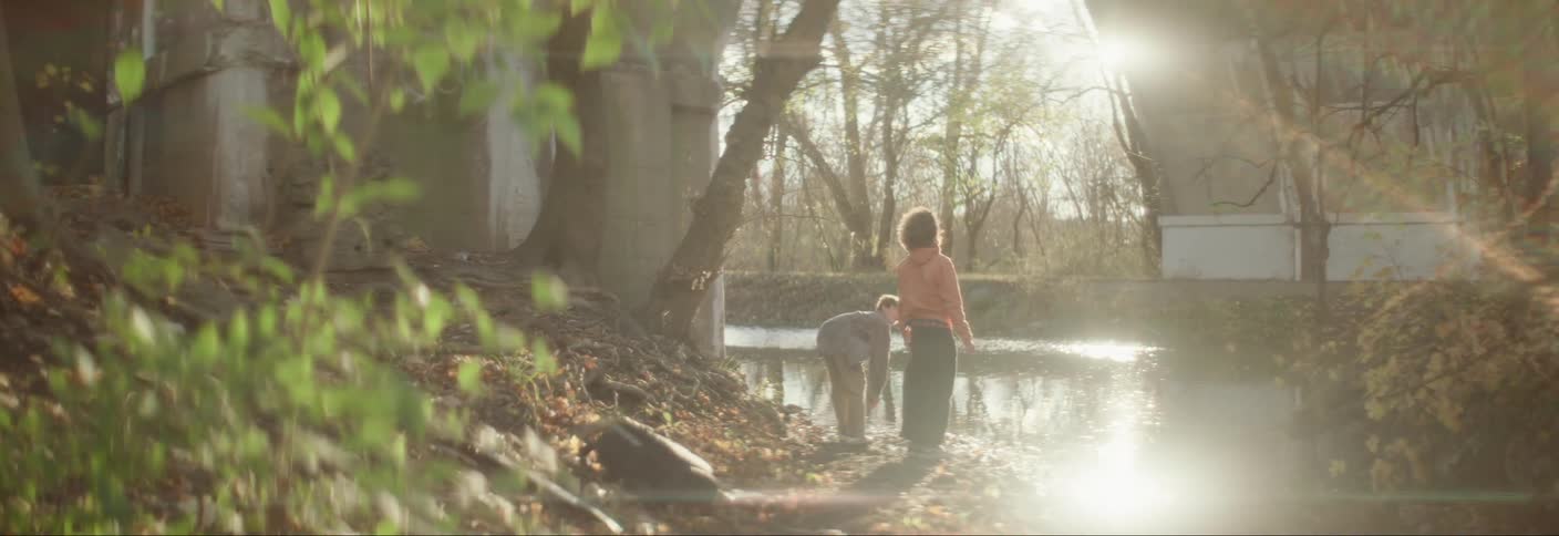 A couple of kids skipping stones on a lake or pond at morning